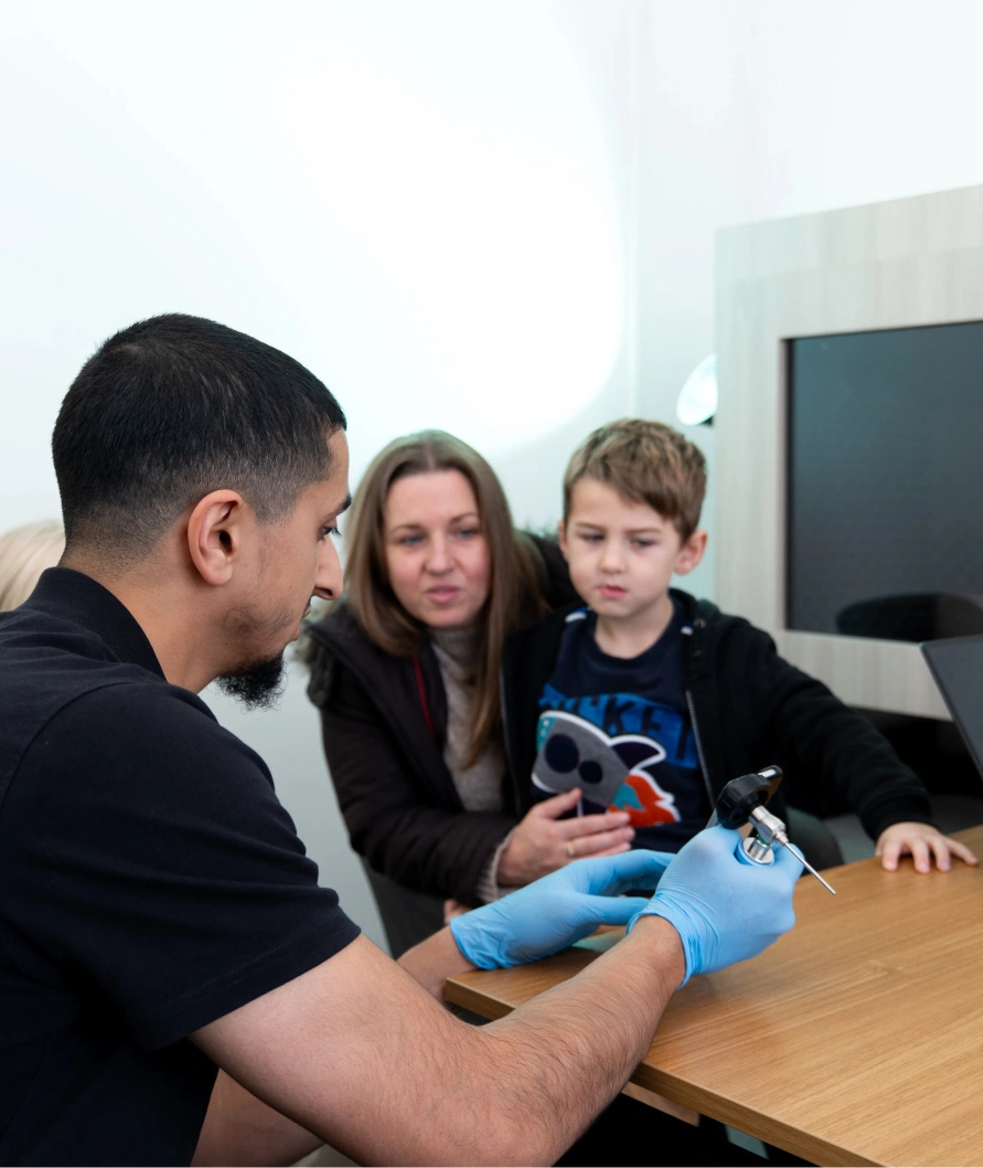 Healthcare professional explaining device to a mother and child in an office setting.