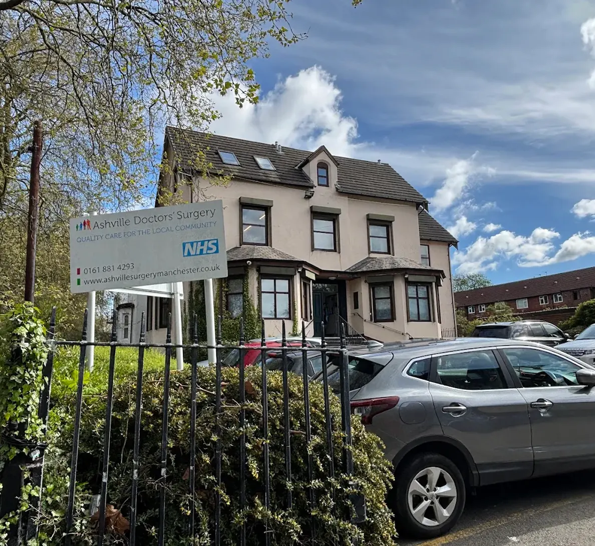 Ashville Doctors' Surgery building with signage and parked cars on a sunny day.