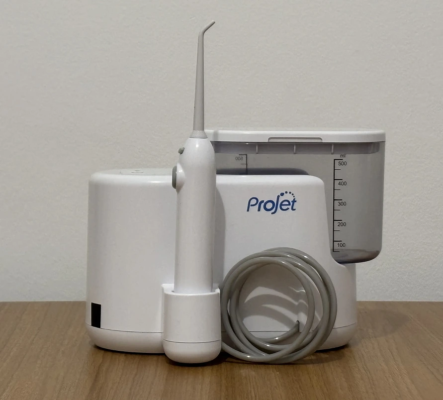 Compact water flosser with detachable nozzle and water tank on a wooden surface, labeled Projet.