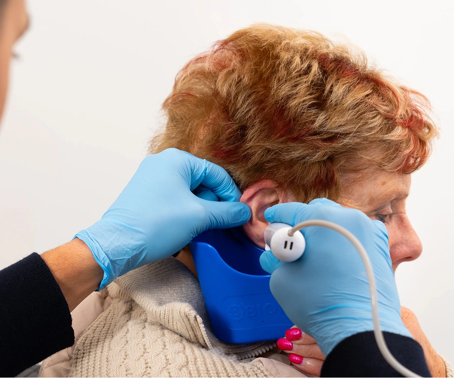 Healthcare professional using an ear irrigation tool on a senior patient for ear cleaning.