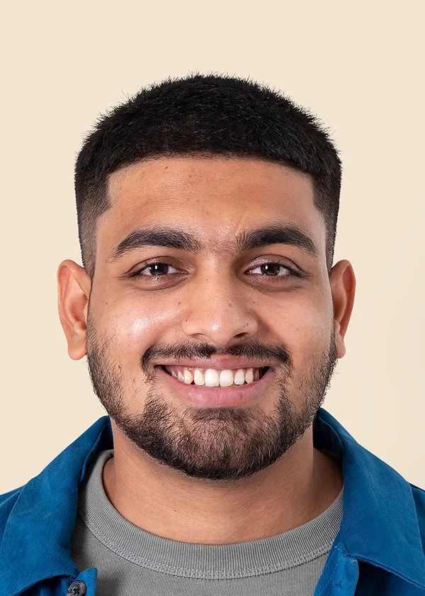 Smiling man with short hair and beard in a blue shirt against a beige background.