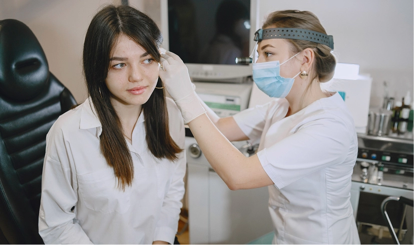 Doctor examining a patient's ear in a clinic setting.