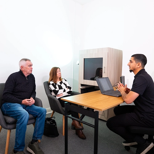 People discussing options at a desk in a modern office setting with a laptop.