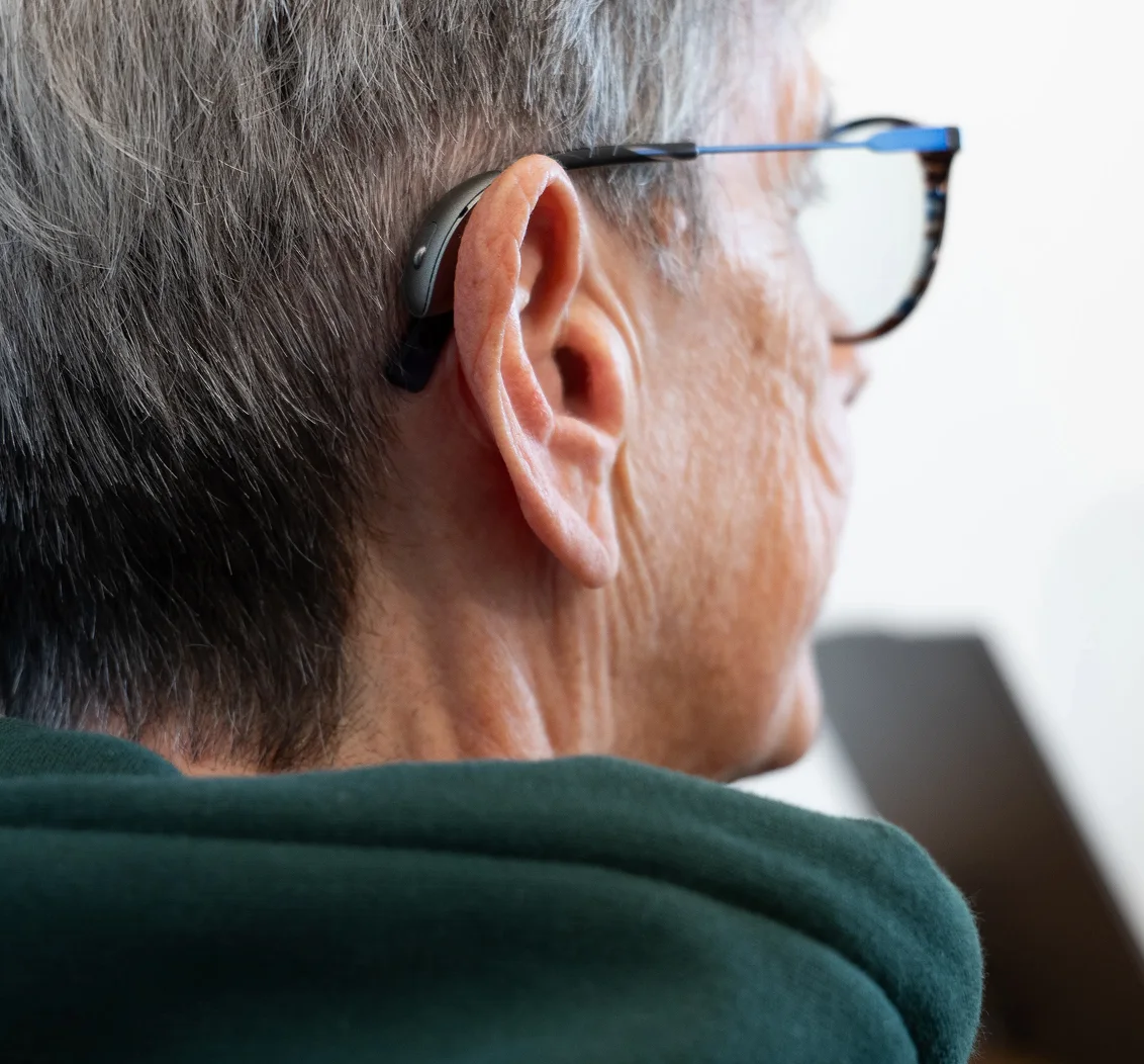 Senior wearing glasses and a hearing aid, enhancing auditory assistance and clarity.
