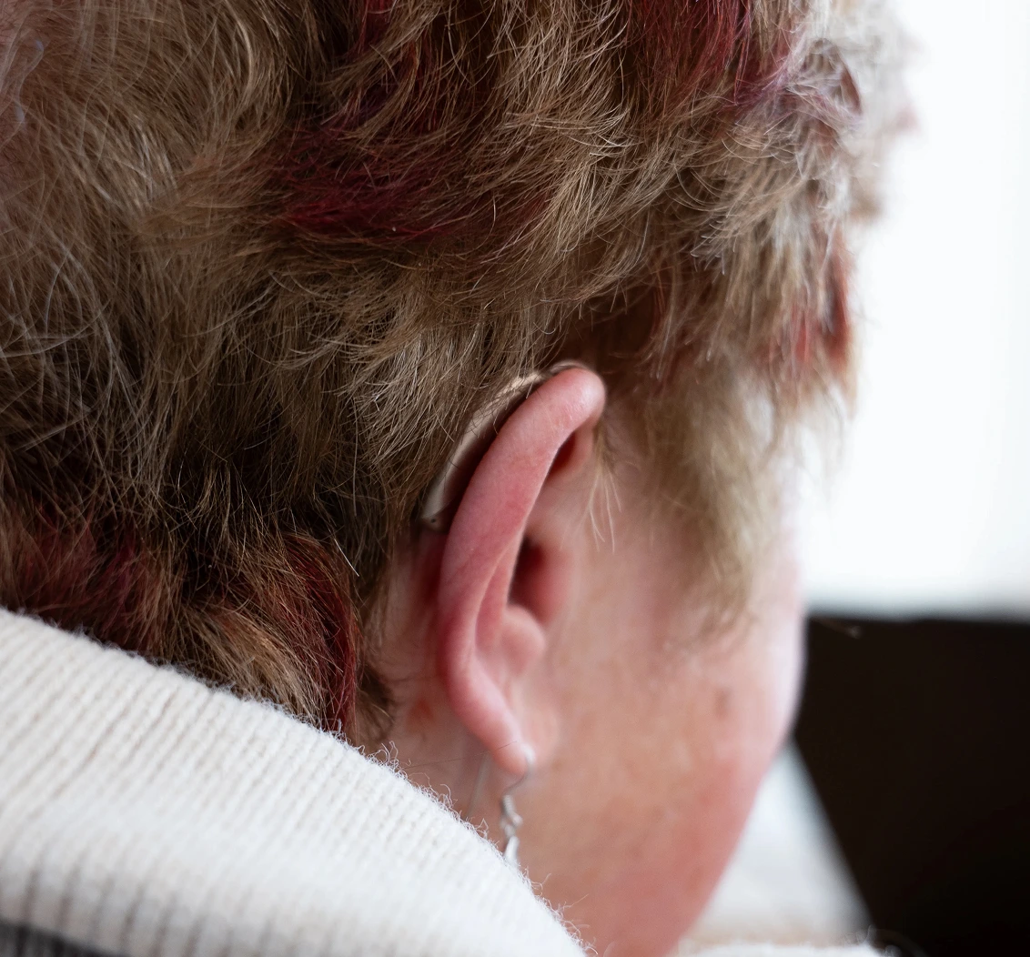 Close-up of a person's ear with a hearing aid, highlighting assistive technology for improved hearing.