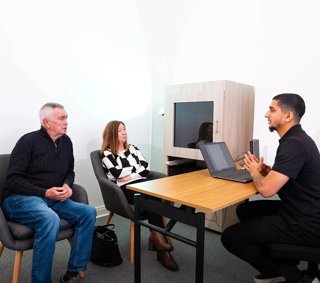 Business meeting with a man discussing plans with a seated couple in a modern office setting.