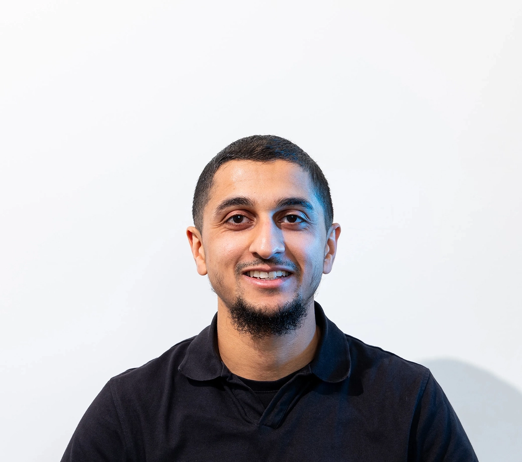 Smiling man in a black shirt against a plain white background.