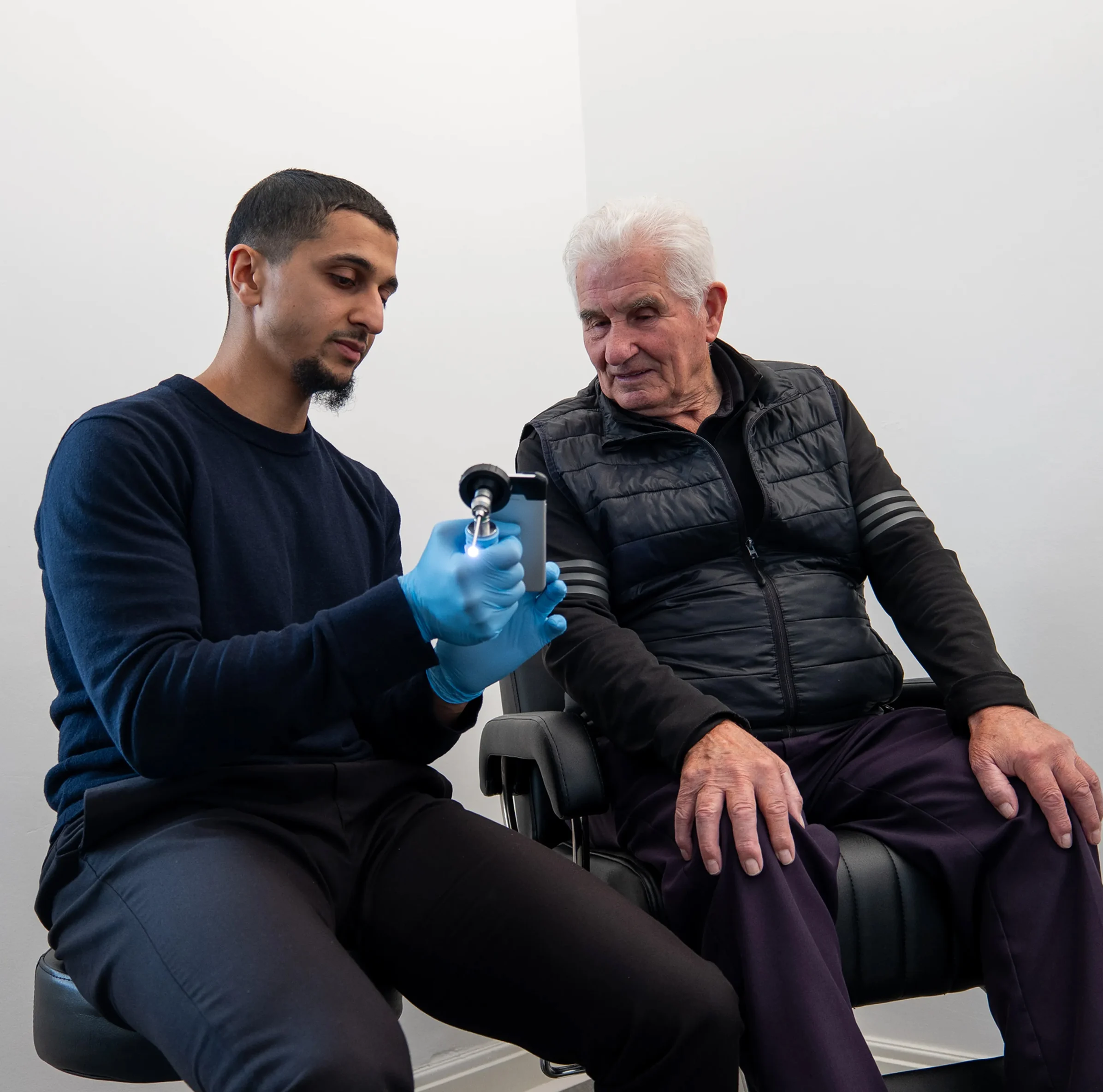 Healthcare professional demonstrating device to elderly patient in medical office.