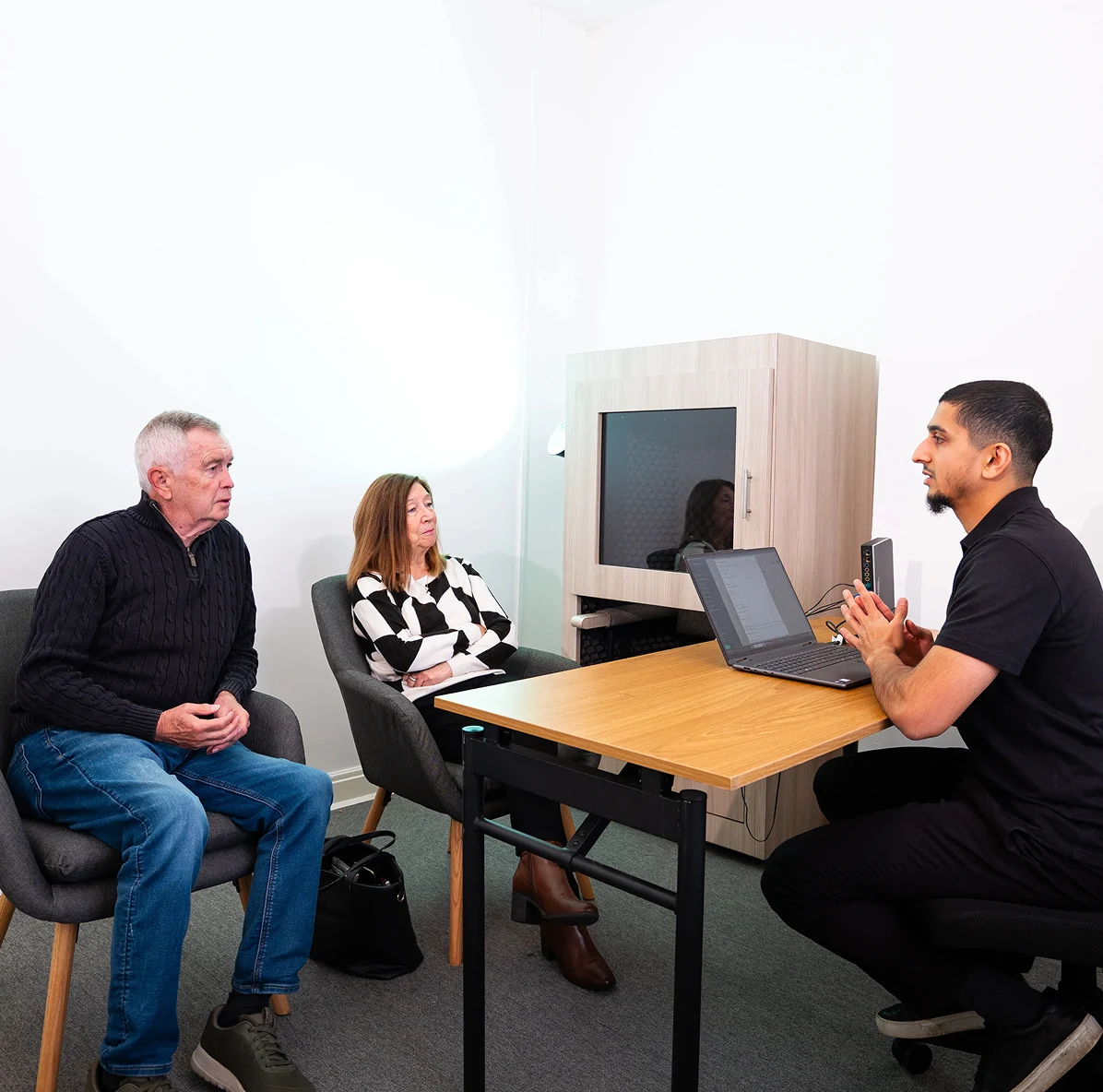 Three people engaged in a serious discussion around a table in a modern office setting.