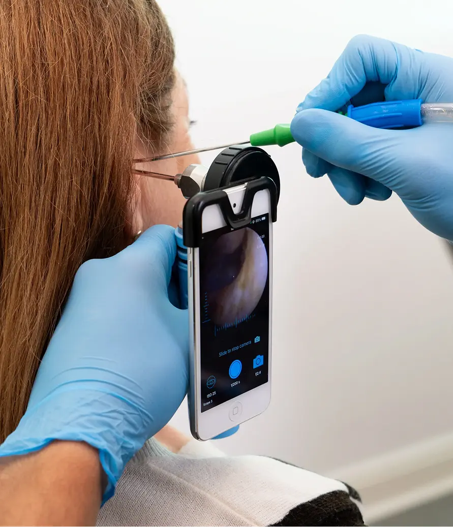 Clinician using a digital otoscope to examine a patient's ear.