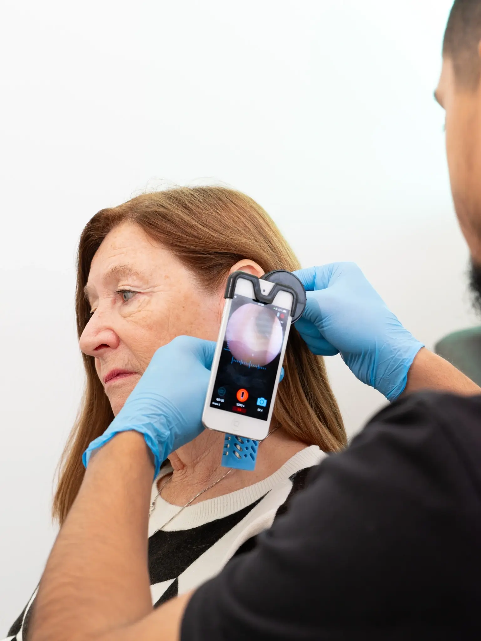 Clinician using a digital otoscope to examine a patient's ear.